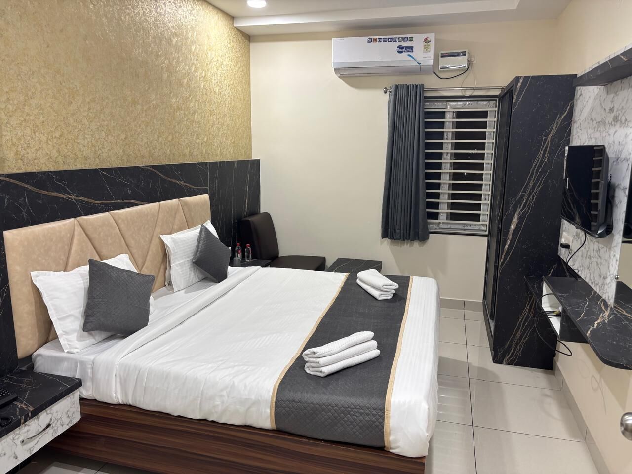 Ein Hotelzimmer mit Bett, Schreibtisch, Stuhl, Fernseher und Klimaanlage.