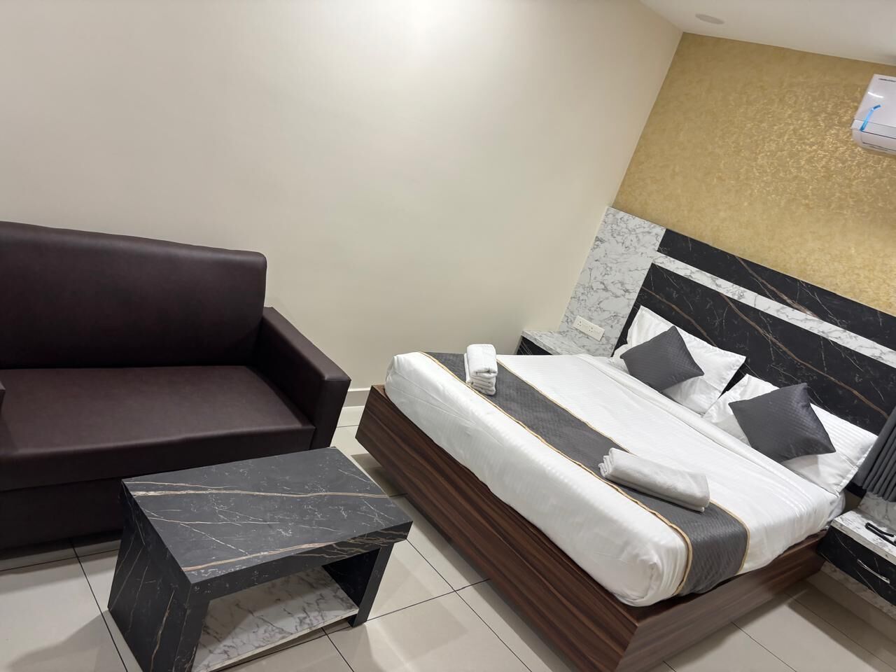 A hotel room with a bed, a sofa, and a small table.