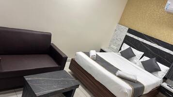 A hotel room with a bed, a sofa, and a small table.