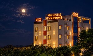 Un edificio de hotel de varios pisos con señalización iluminada que indica 'HOTEL GVR PRIME' y 'HABITACIONES DE LUJO' de noche.