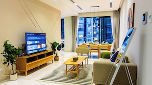 A modern living room with a flat-screen TV, a sofa, a dining table, and a large window with a city view. - The Manor KLCC (Kuala Lumpur)