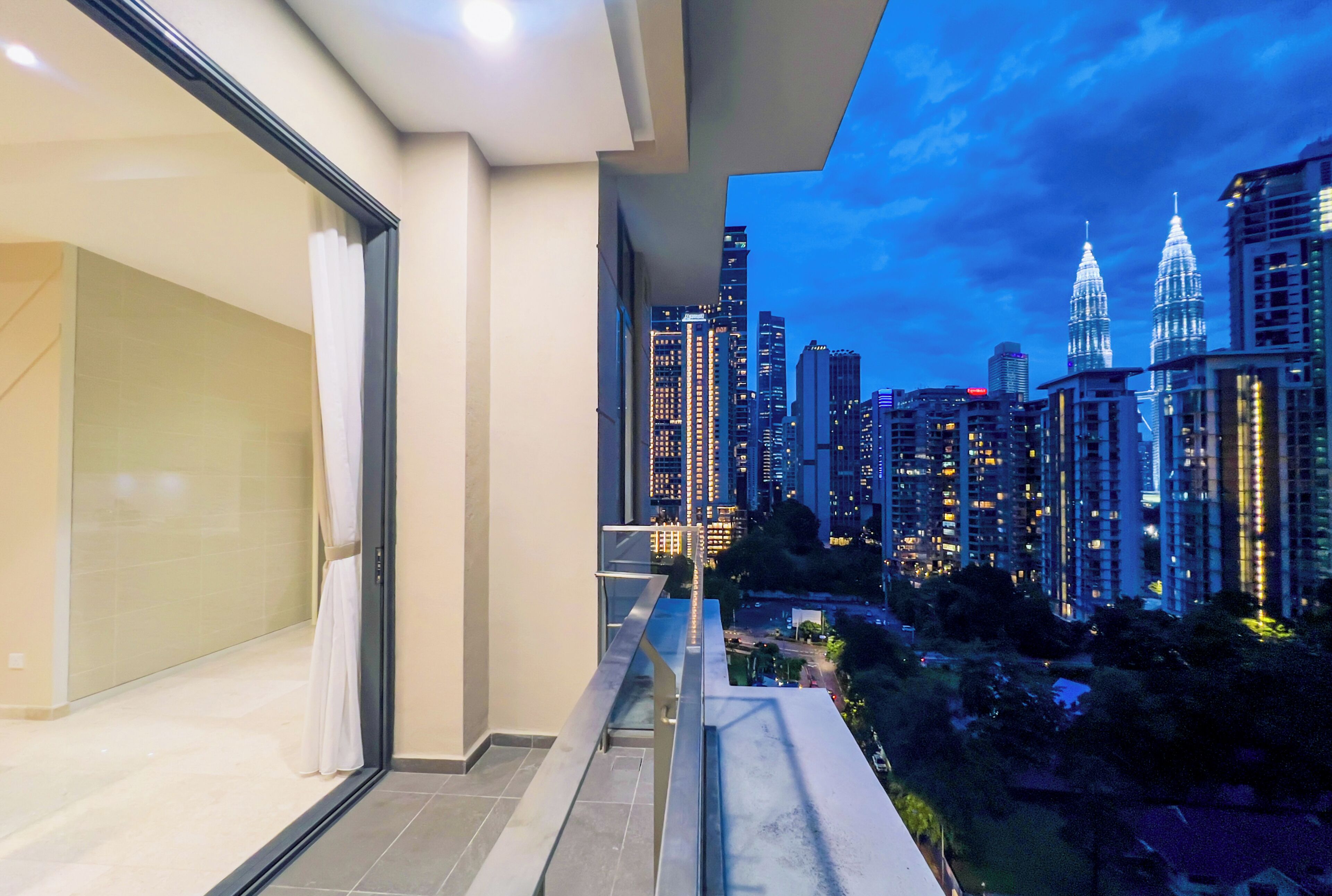 A balcony with a cityscape view, including high-rise buildings and a prominent tower.