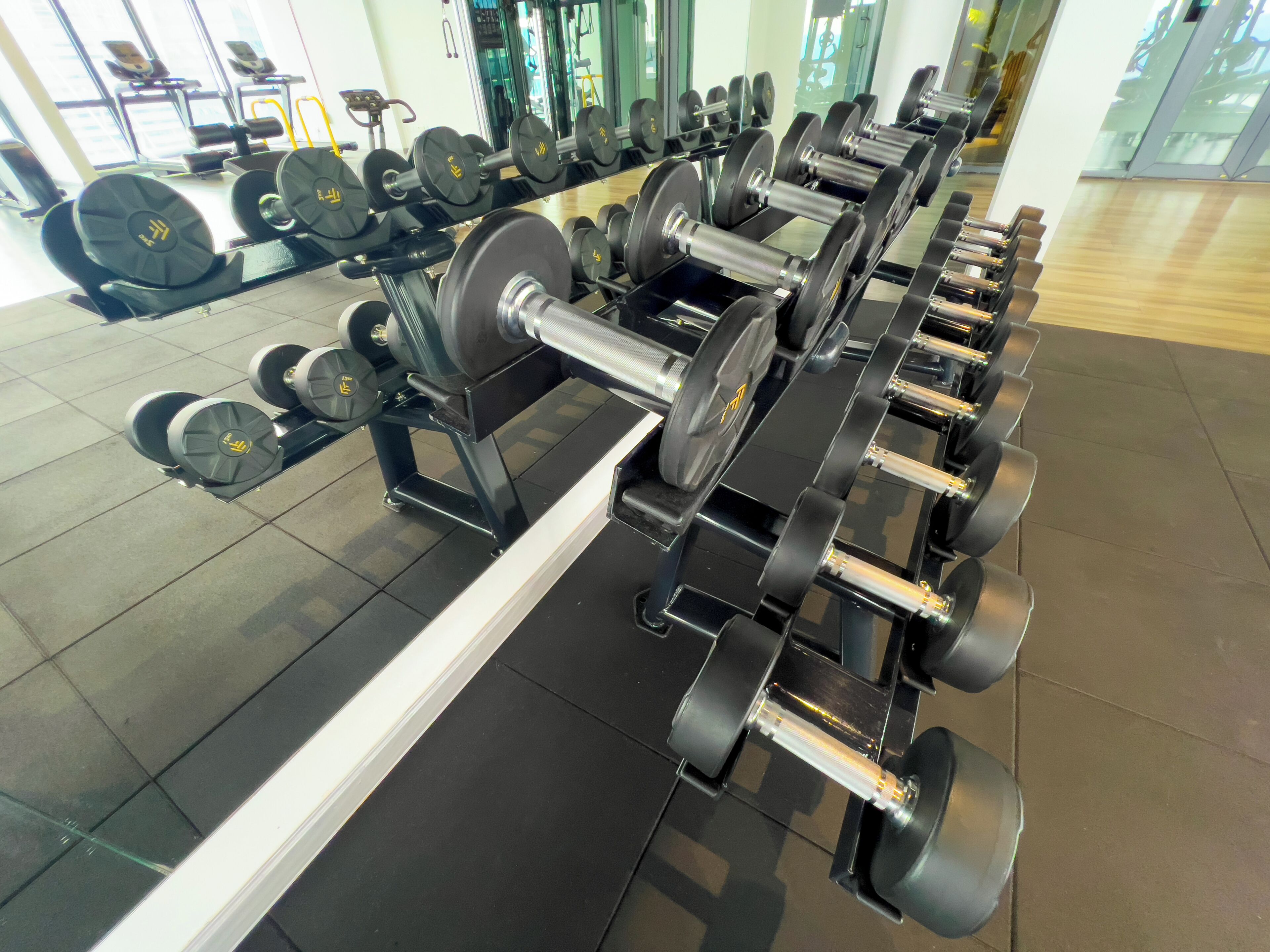 A gym with multiple rows of dumbbells and weight plates.