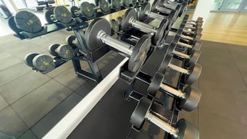A gym with multiple rows of dumbbells and weight plates.