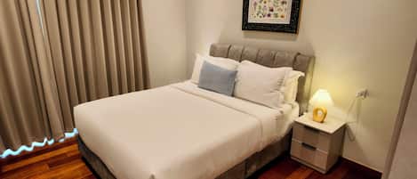 A neatly made bed with a headboard, a bedside table with a lamp, and a framed floral artwork on the wall.