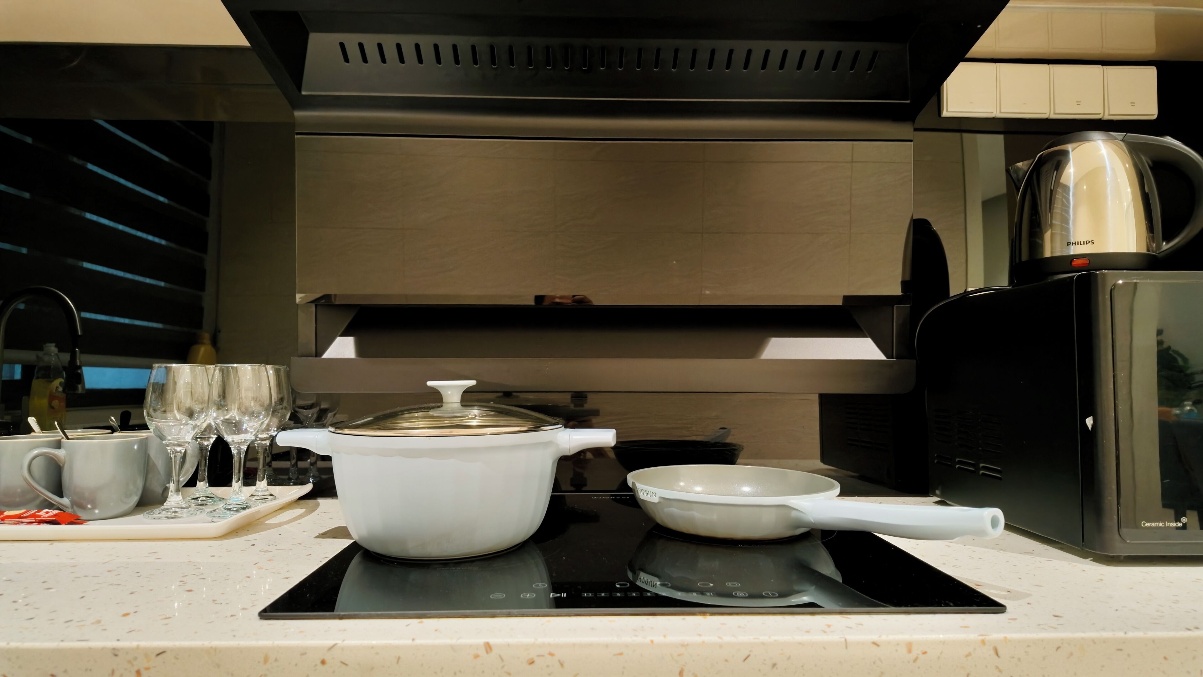 Cocina moderna con horno empotrado, cafetera y hervidor sobre la encimera.