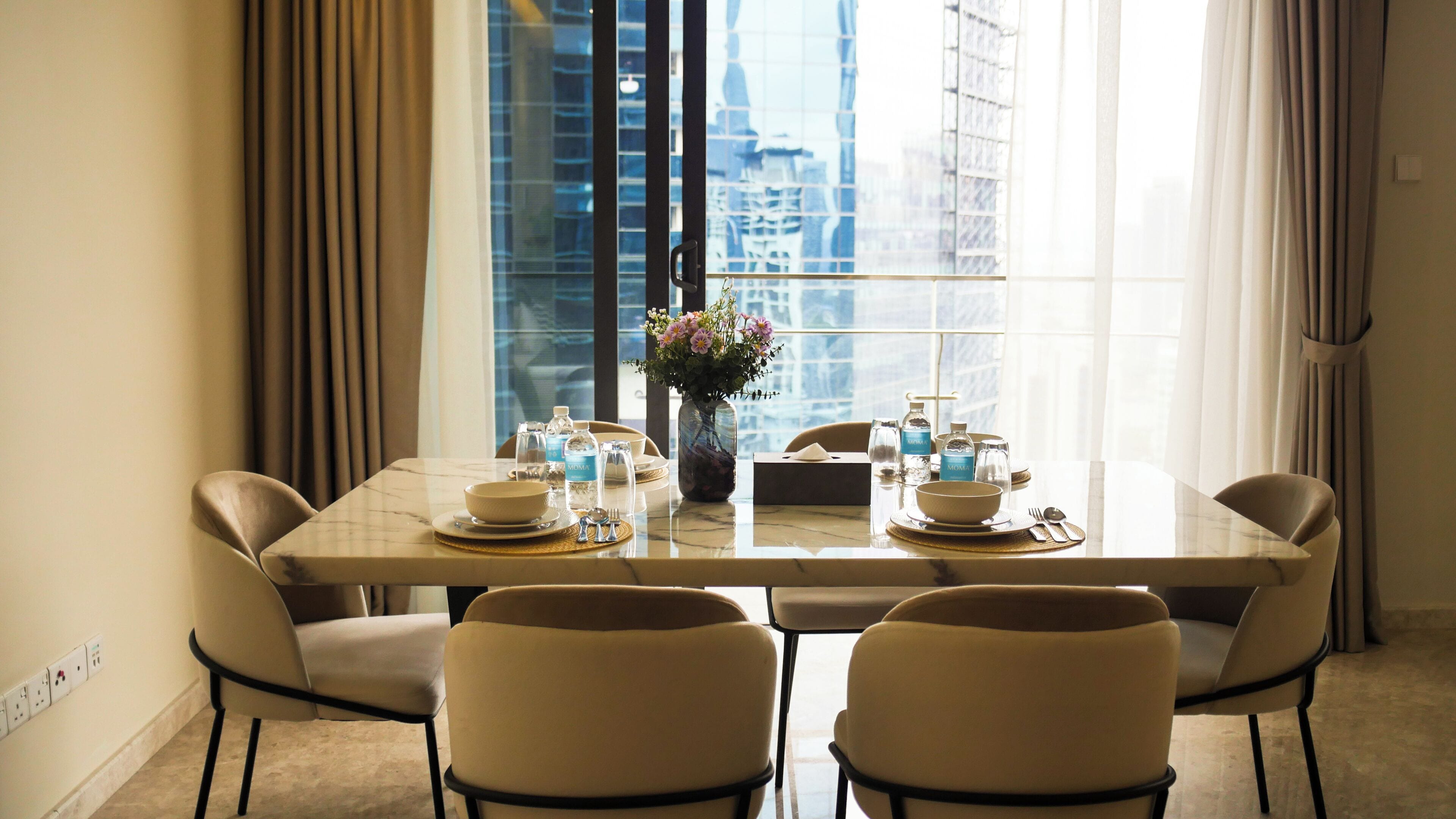 A hotel dining room with a marble table set for four, including water bottles and a vase with flowers.