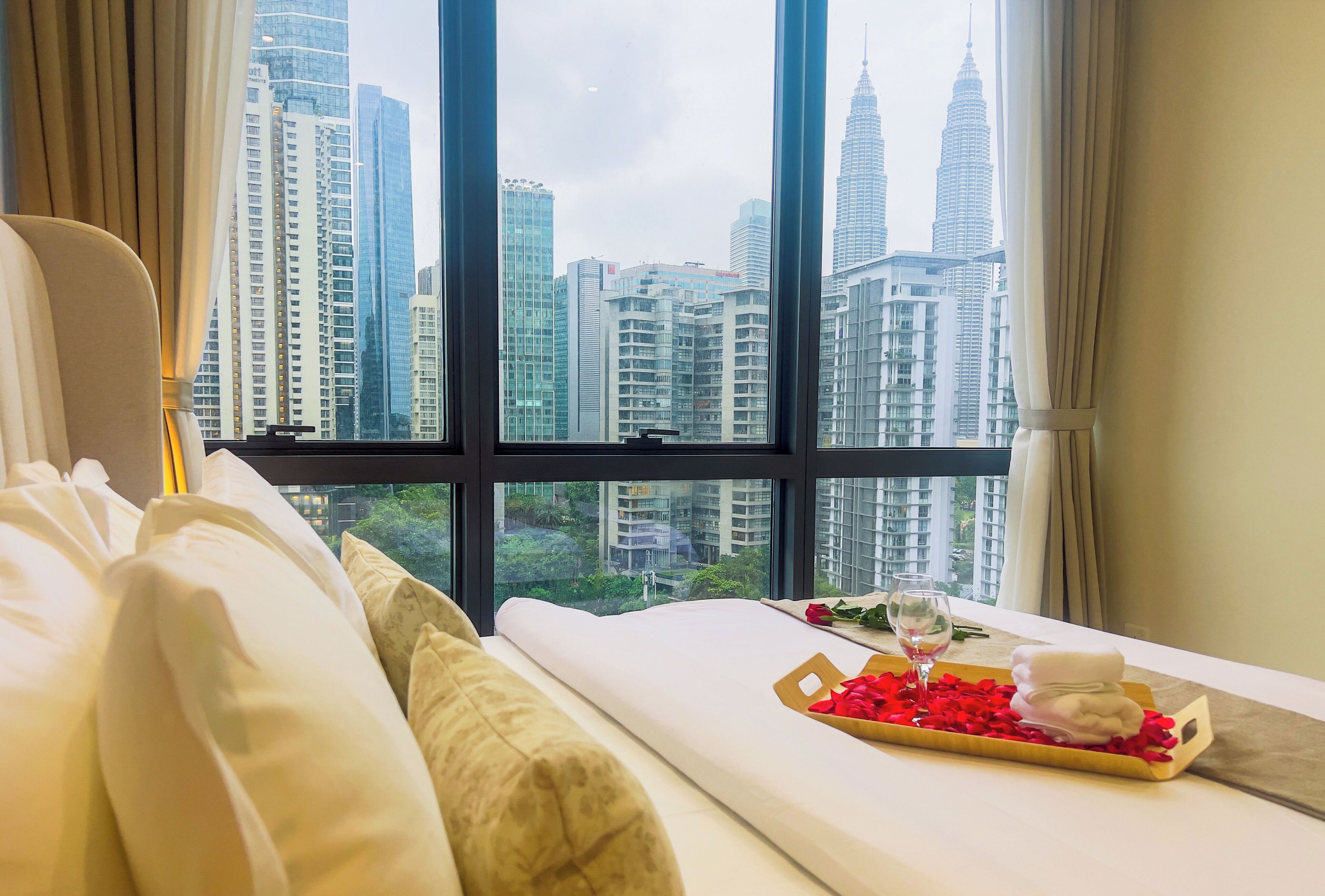 A hotel room with a large window offering a view of high-rise buildings and a cityscape.
