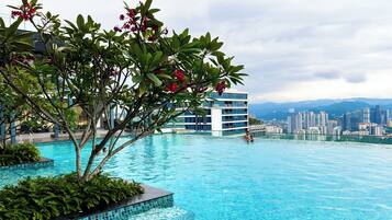 A swimming pool with a cityscape view, surrounded by greenery and modern buildings.