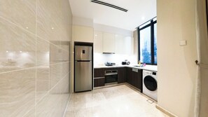 A modern kitchen with a stainless steel refrigerator, built-in oven, microwave, and a washing machine. - The Manor KLCC (Kuala Lumpur)