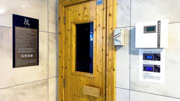 Een saunadeur met een houten paneel en een glazen raam, een bord met saunaregels en een bedieningspaneel met een digitaal scherm.