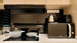 Uma cozinha com fogão, panelas, micro-ondas e cafeteira.