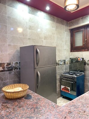 A kitchen with a stainless steel refrigerator, a gas stove, and a granite countertop. - Chalet in Horus Village and Golden Sands, North Coast (North Coast)