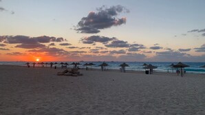 Une plage avec des parasols et un coucher de soleil.