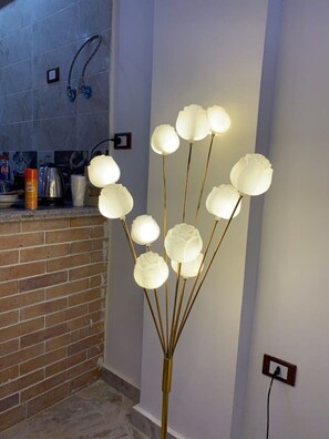 A modern kitchen with a brick backsplash, a countertop with various items, and a unique light fixture with multiple spherical bulbs. - Chalet in Horus Village and Golden Sands, North Coast (North Coast)