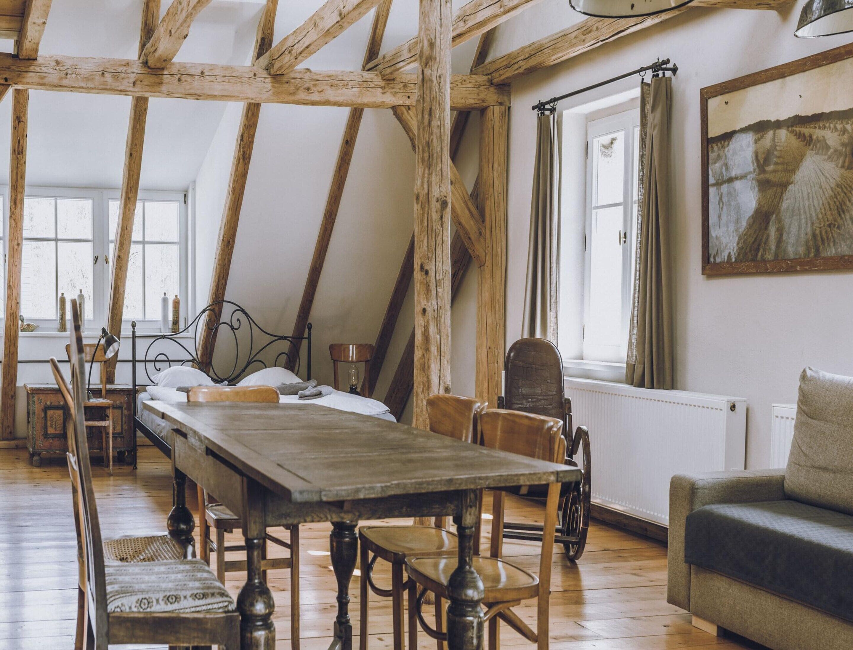 A rustic room with a wooden table, a bed, and a sofa.