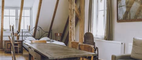 A rustic room with a wooden table, a bed, and a sofa.