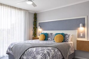 A bedroom with a bed, a ceiling fan, a wall-mounted light, and a decorative plant. - Sea Breeze 2-bedroom apartment with AC in Mandurah (Mandurah)