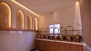 A hotel reception area with a marble counter, ornate wall panels, and a window. - Ramanjaneya Eecutive Hotel Udupi (Samudrapur)