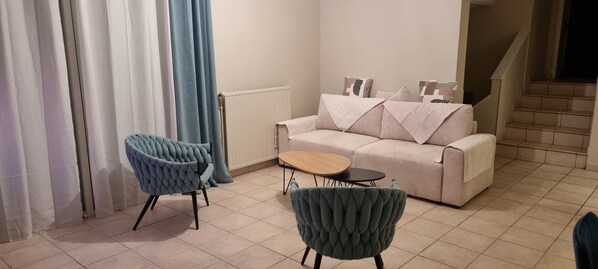 Ein Wohnzimmer mit einer Couch, zwei Sesseln, einem kleinen Tisch und einer Heizung.