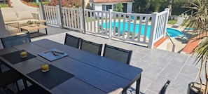 Eine Terrasse mit Pool, Sitzgelegenheiten und einem Tisch mit Getränken.