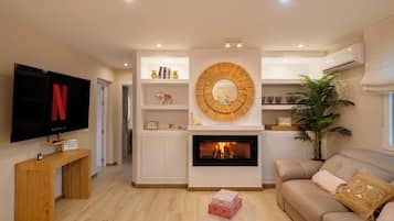 Una sala de estar moderna con una televisión de pantalla plana, una chimenea y un sofá.