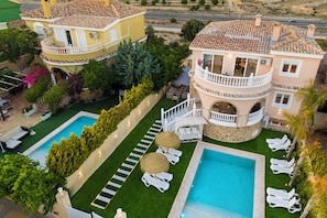 A multi-story building with a pool, outdoor seating, and a well-maintained garden.