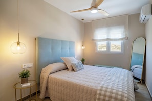 A bedroom with a bed, bedside tables, a ceiling fan, and a window with curtains.