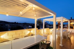 Eine Außenpatio mit weißer Pergola, einer Sitzecke und Blick auf die Landschaft.