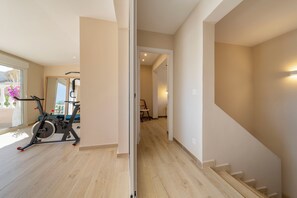 A modern interior with a wooden floor, a staircase, and a home gym area.