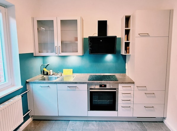 A compact kitchen with a built-in oven, a sink, and a microwave.
