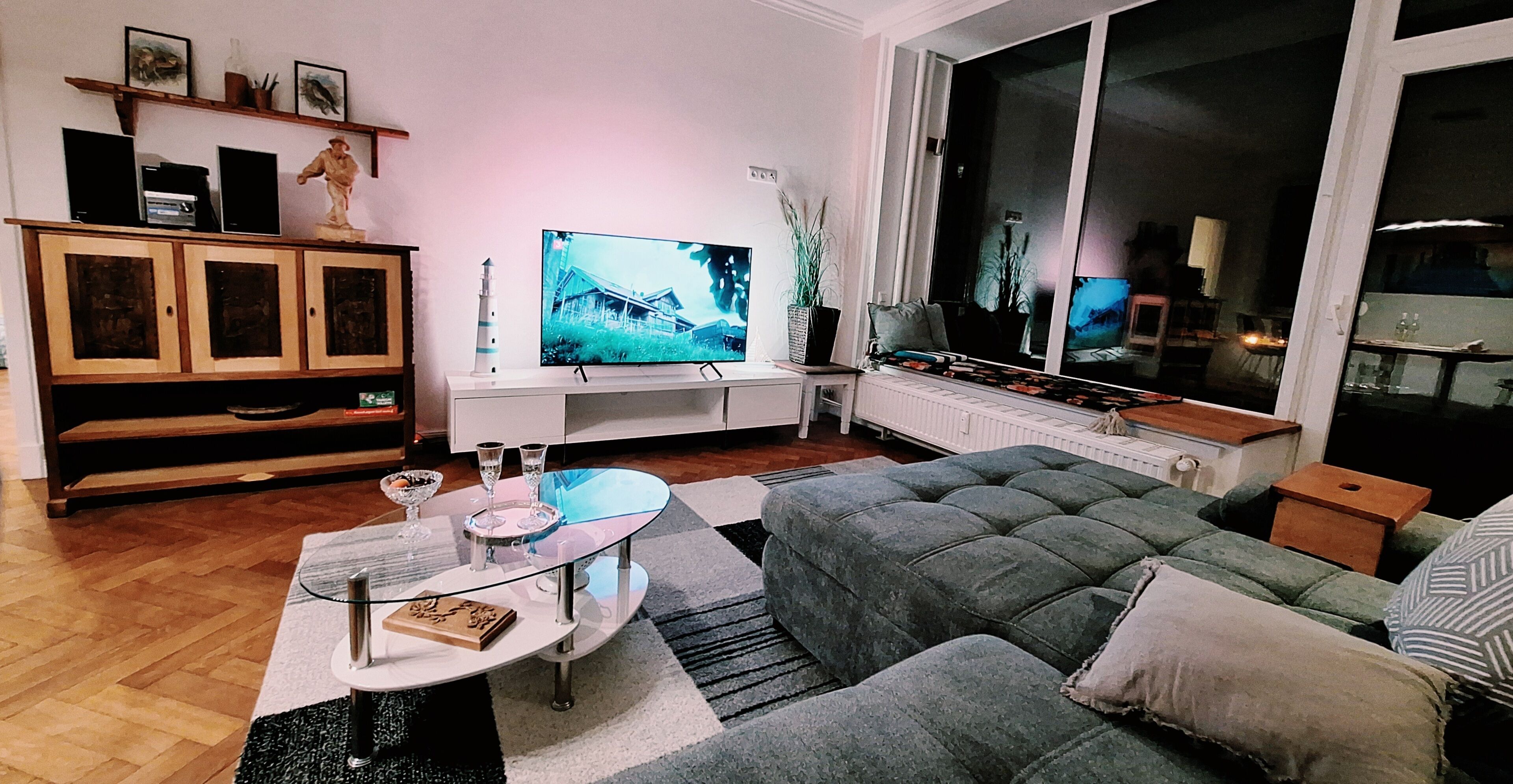 A living room with a television, a glass coffee table, a sofa, and a cabinet.