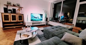 A living room with a television, a glass coffee table, a sofa, and a cabinet.