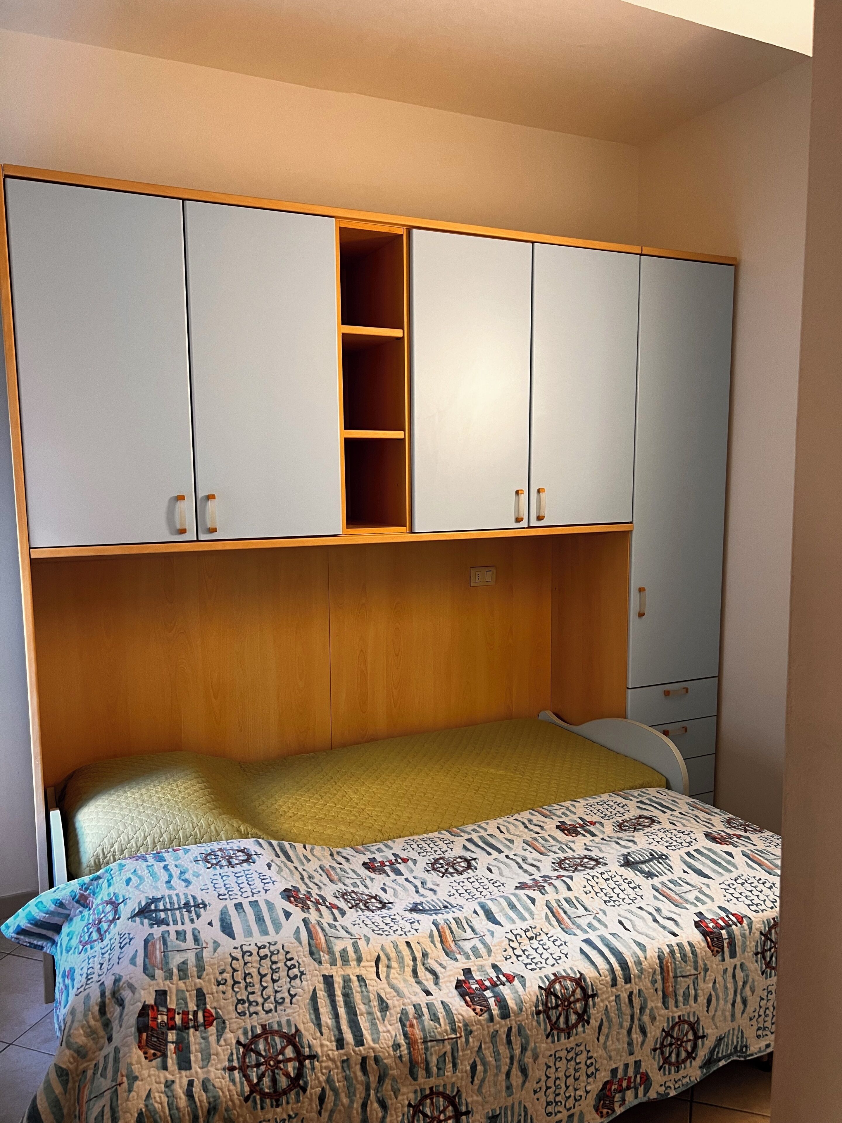 Un dormitorio con una cama, un armario con varios compartimentos y una mesita de noche.