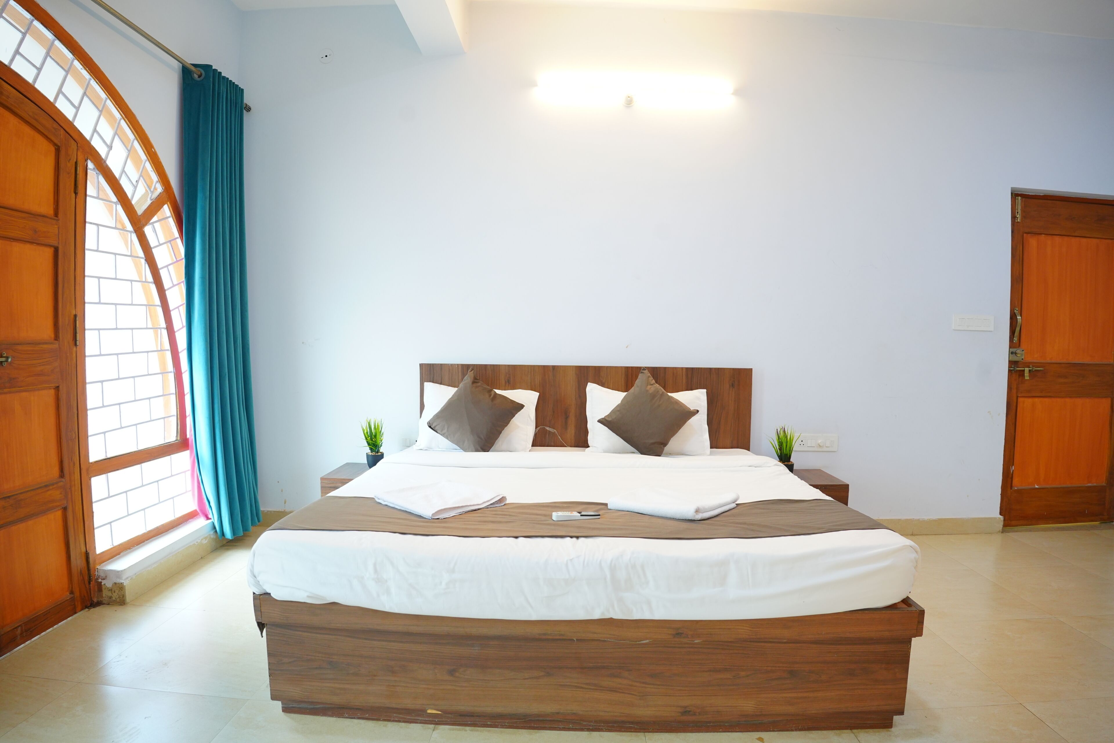 Ein Schlafzimmer mit einem Holzbett, weißer Bettwäsche und zwei Blumentöpfen auf den Nachttischen.