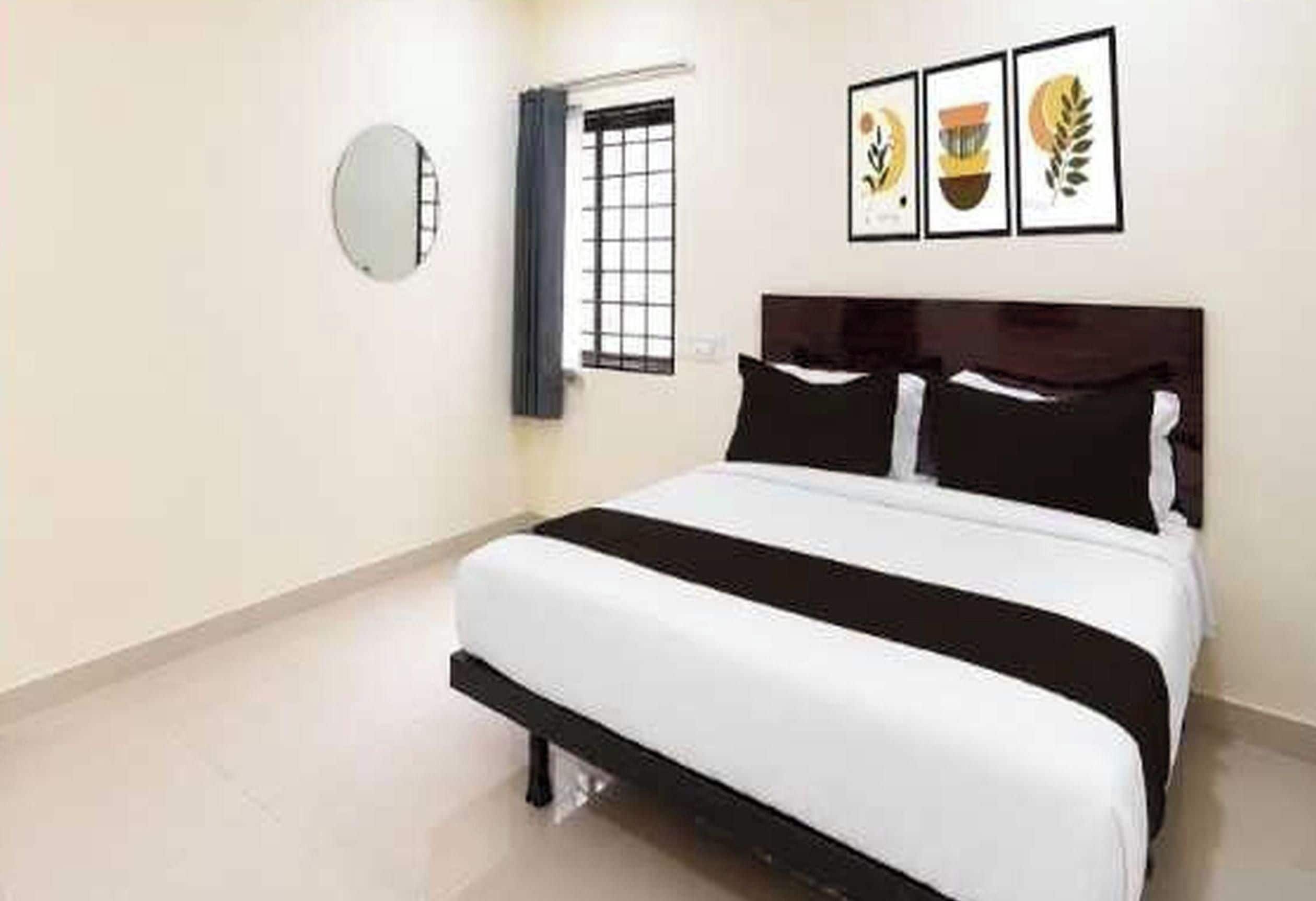 Une chambre d’hôtel avec un lit, une fenêtre donnant sur un paysage agréable et un miroir fixé au mur.