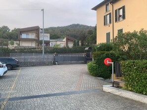 A paved driveway leading to a gated entrance with a car parked on the left.