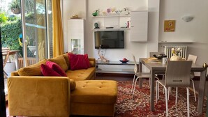 Ein modernes Wohnzimmer mit einer Couch, einem Esstisch und einem Fernseher.