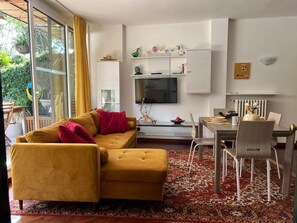 Ein modernes Wohnzimmer mit einer Couch, einem Esstisch und einem Fernseher.