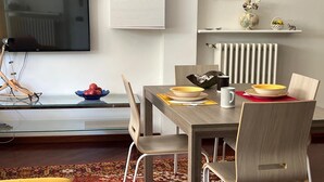 Ein zeitgemäßer Essbereich mit Holztisch, Stühlen und einem an der Wand montierten Flachbildfernseher.