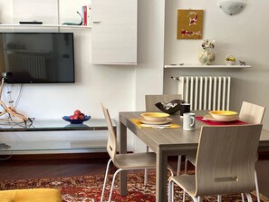 Ein zeitgemäßer Essbereich mit Holztisch, Stühlen und einem an der Wand montierten Flachbildfernseher.