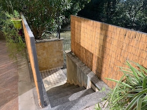 A staircase leading to a covered area with a bamboo wall and a tiled floor.