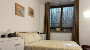 Ein Schlafzimmer mit einem Bett, Nachttischen, einer Kommode und einem Fenster mit Vorhängen.