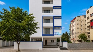 Un immeuble à plusieurs étages, doté d’une façade blanche et de touches de couleur bleue, avec des balcons et une entrée au niveau du sol.
