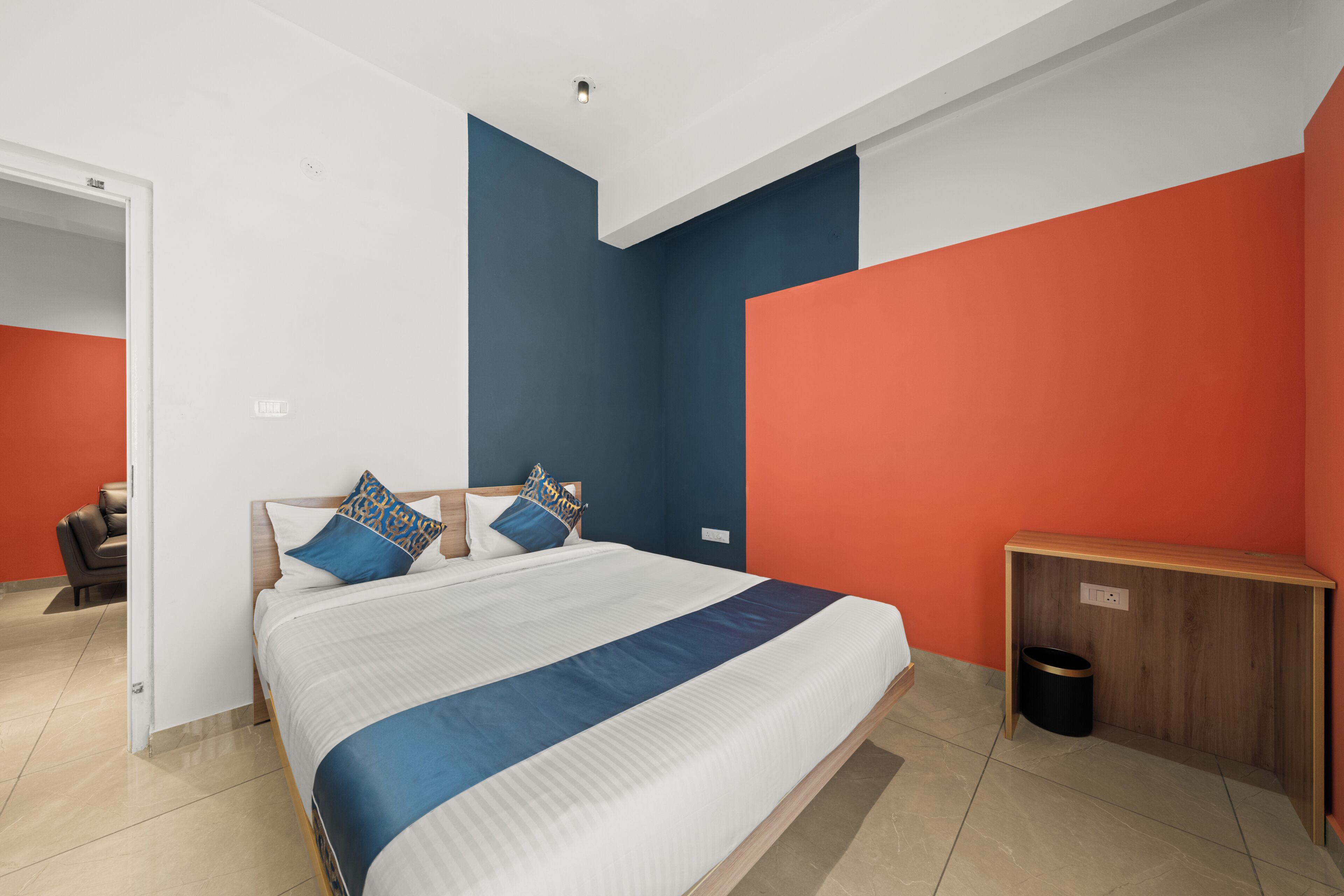 A modern bedroom with a large bed, two pillows, a nightstand, and a wooden bench.