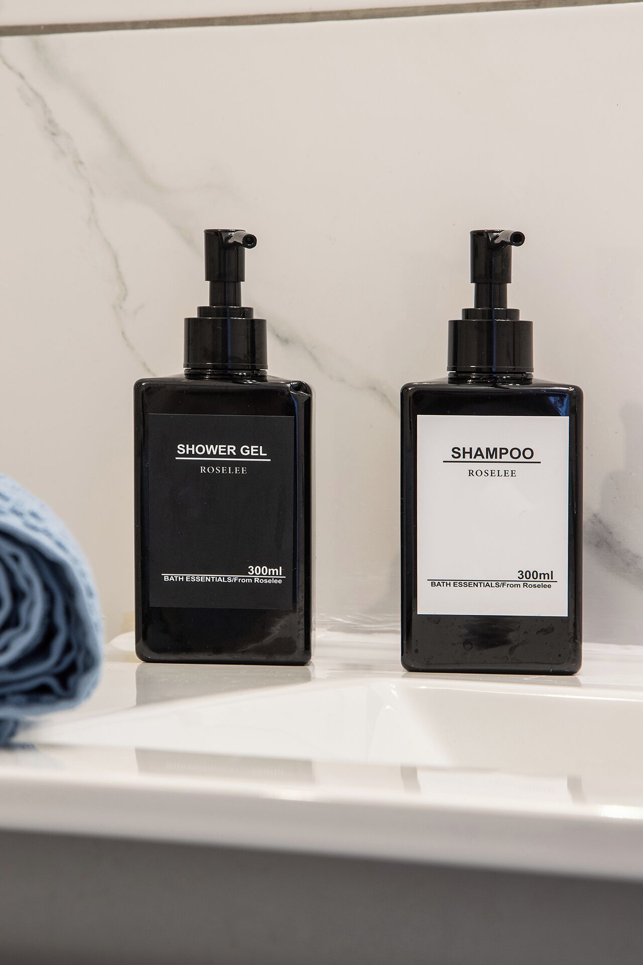 Two black bottles of shower gel and shampoo on a white surface.
