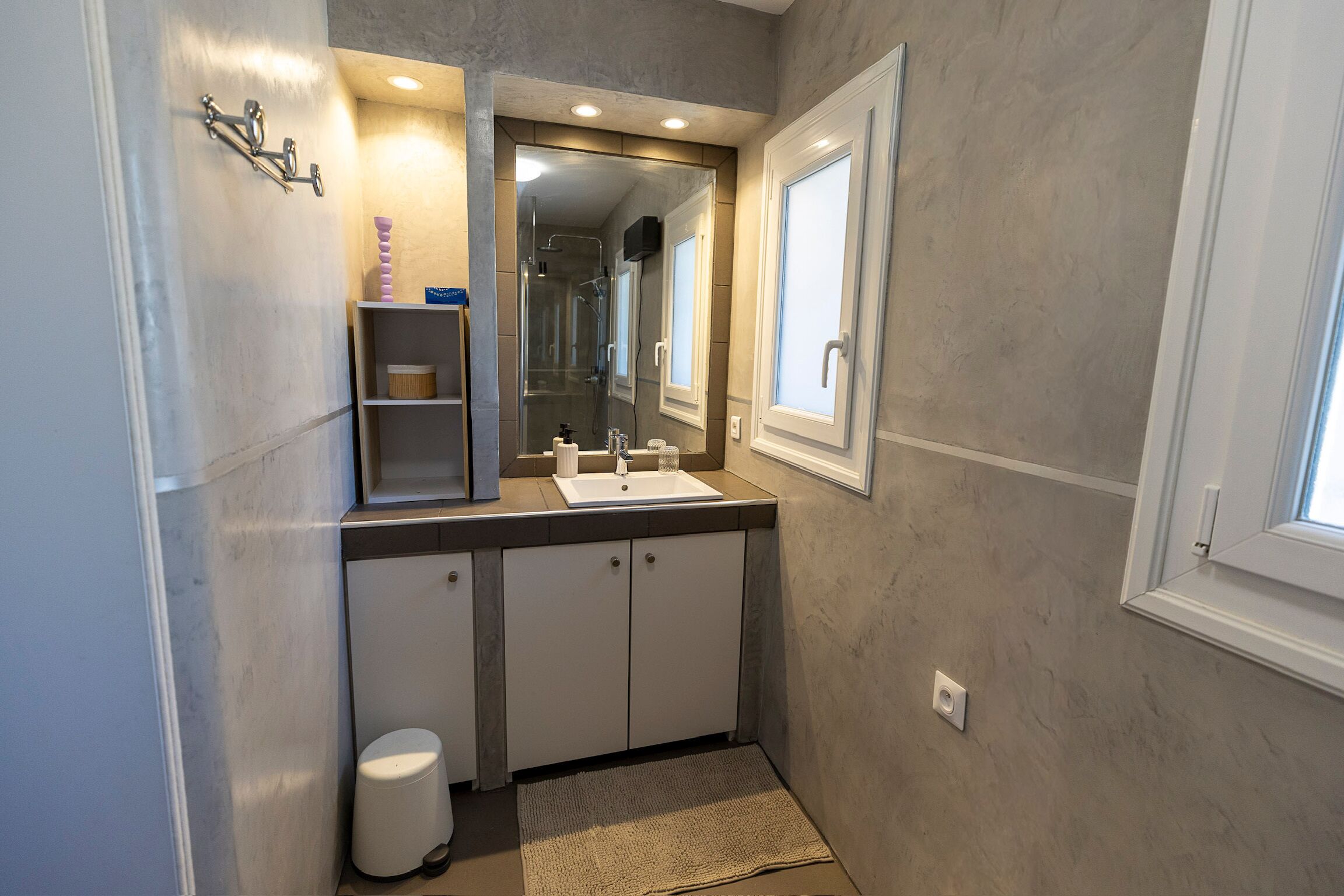 Ein Badezimmer mit großem Spiegel, Waschbecken, Dusche und Toilette.