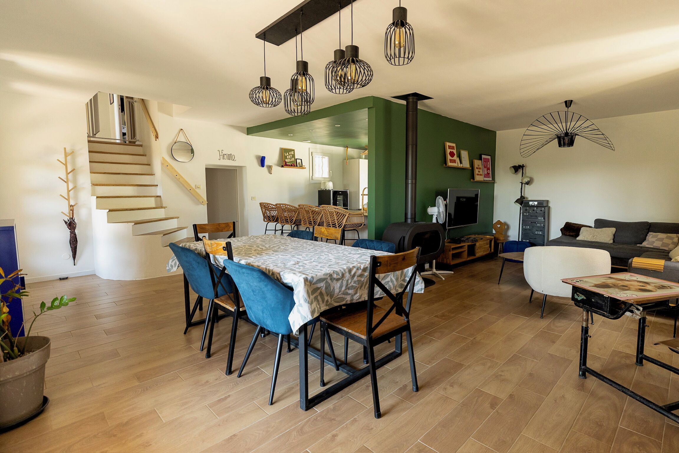 A spacious living area with a dining table, chairs, a sofa, and a staircase.