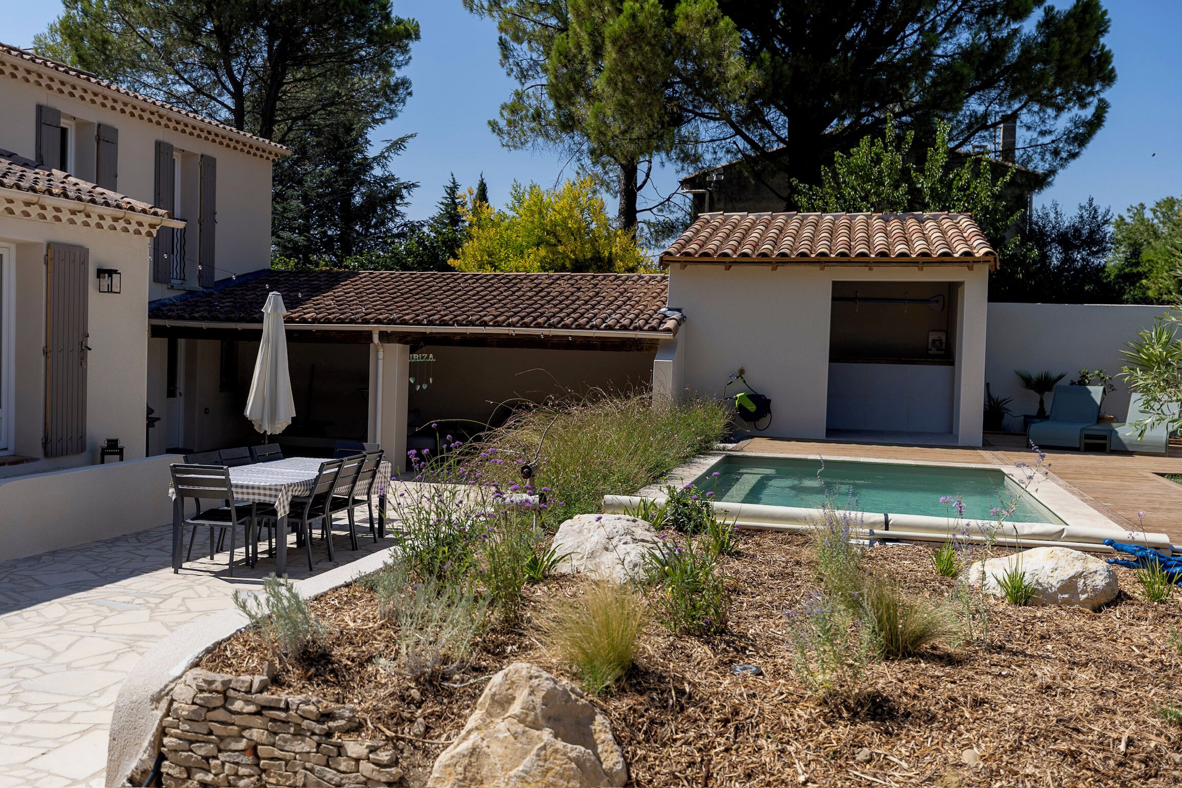 A patio area with a table and chairs, a swimming pool, and a covered outdoor seating area.