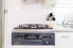 A kitchen with a gas stove, oven, and a coffee machine on a stand. - b&Dotonbori 1 (Chuo Ward)